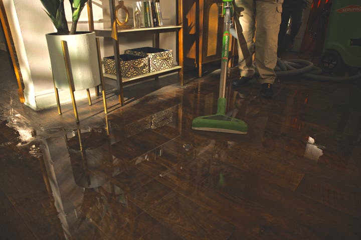 A wet floor of a residential home being cleaned by a SERVPRO employee.